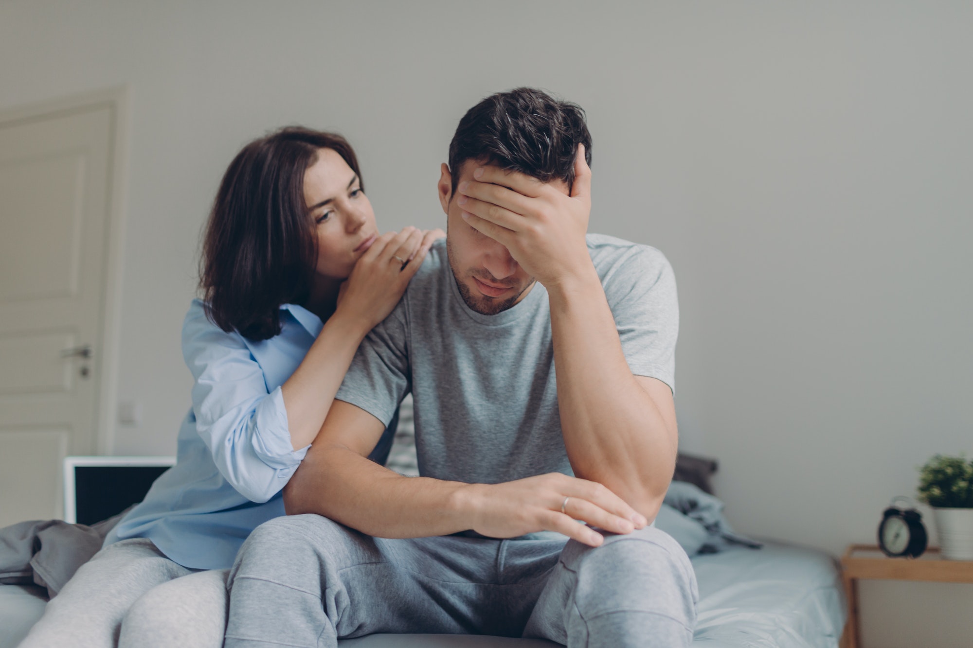 Female consoles her sad boyfriend who has depression and some problems, pose at bedroom on bed